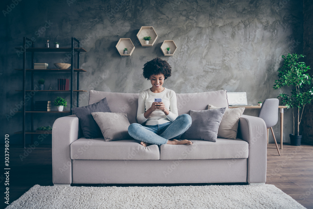 Photo of pretty dark skin curly lady homey domestic atmosphere texting telephone with friends reading instagram posts sitting comfy couch casual outfit flat loft indoors - obrazy, fototapety, plakaty 