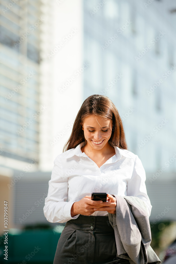 Young businesswoman in city. Beautiful woman in suit with phone outdoors