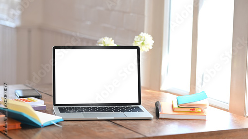 Mockup laptop computer isolated white screen on creative workspace. © Prathankarnpap