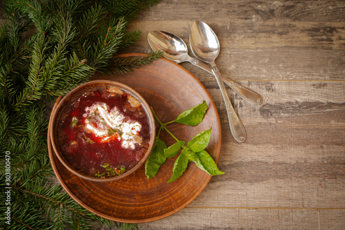 Homemade russian, ukrainian and belarussian national soup - red borscht made of beetrot, vegetables and meat with sour cream on a wooden table top view photo