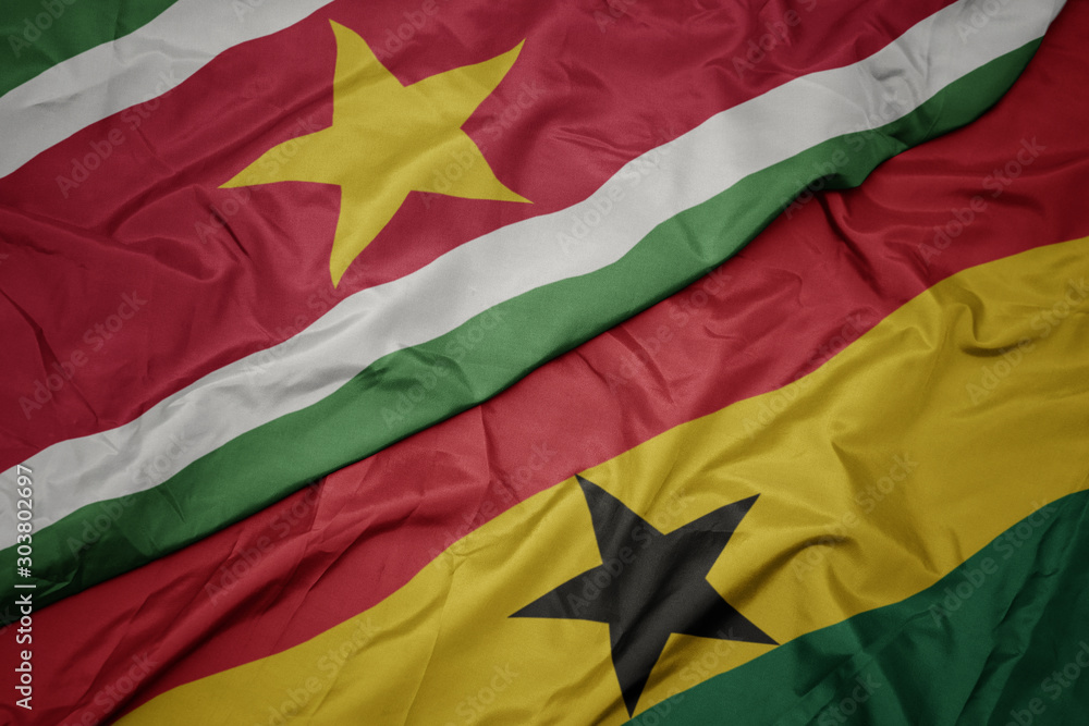 waving colorful flag of ghana and national flag of suriname. waving colorful flag of ghana and national flag of suriname.