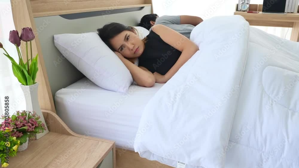Asian unhappy young couple in the bedroom experiencing emotional stress and problems in relationship, ignore to looking at each other and unwilling to communicate, upset thoughtful spouses avoiding ta Asian unhappy young couple in the bedroom experiencing emotional stress and problems in relationship, ignore to looking at each other and unwilling to communicate, upset thoughtful spouses avoiding ta