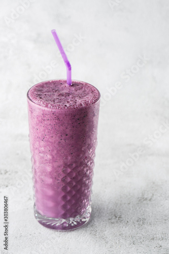 Obraz na płótnie Blueberry smoothie or black currant purple milkshake in glass on bright marble background. Overhead view, copy space. Advertising for milkshake cafe menu. Coffee shop menu. Vertical photo. w salonie