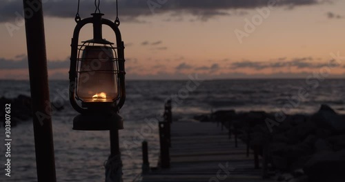 Wooden boat dock bridge and old oil lantern burning on sea shore photo