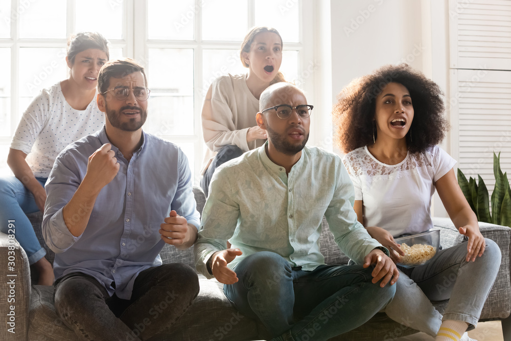 Young worried best friends gathered on sofa, watching football match. Young worried best friends gathered on sofa, watching football match.
