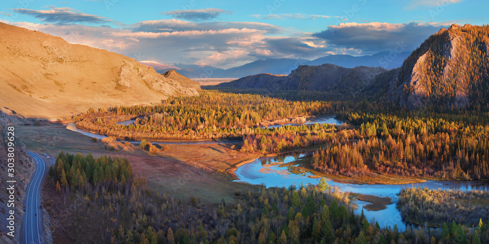 A river flows meandering along a picturesque valley. Chuya River in the Altai Mountains. Bright evening light. Panoramic view. 