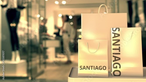 Paper shopping bags with Santiago caption against blurred store entrance. Retail in Chile related 3D animation photo