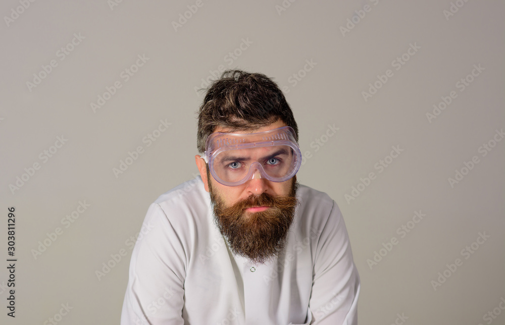 Fototapeta premium Working man in uniform and safety glasses. Bearded man in protective glasses and robe. Confident handsome man scientist in uniform and protective glasses. Handsome male doctor in protective glasses.