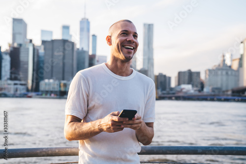 Man with smartphone looking ahead and laughing