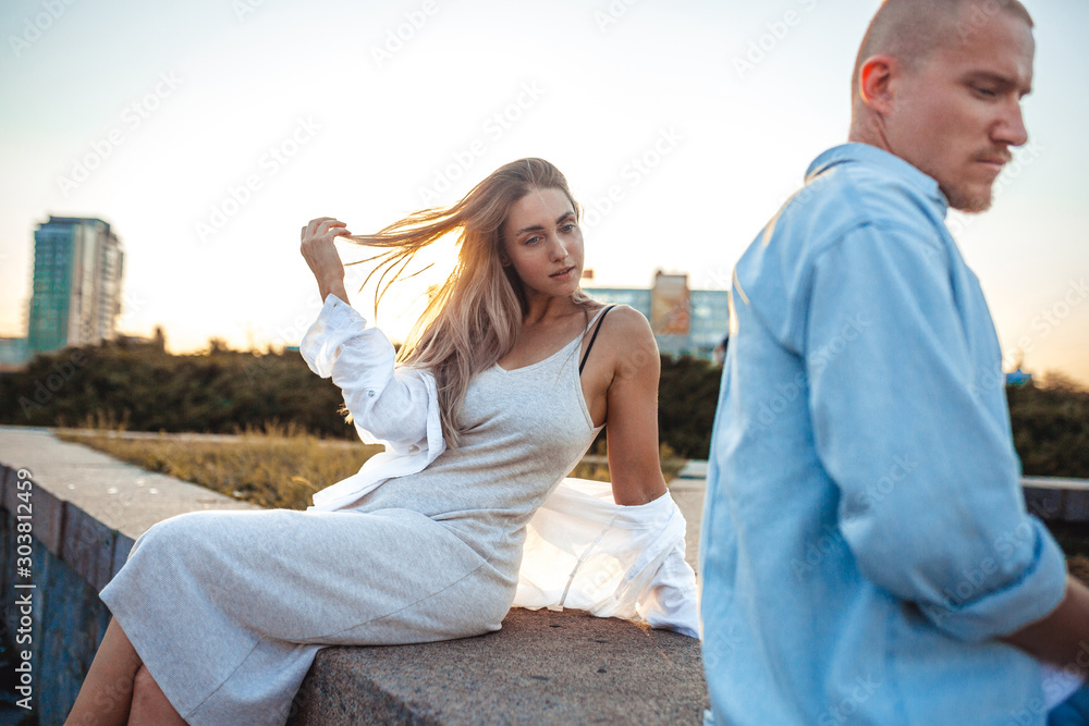 Tanned young caucasian couple, modern lovestory in film grain effect and vintage style. Sunset time. Walking on the city's street, summer evening and sunlight. Honeymoon concept. Toned in teal orange. Tanned young caucasian couple, modern lovestory in film grain effect and vintage style. Sunset time. Walking on the city's street, summer evening and sunlight. Honeymoon concept. Toned in teal orange.