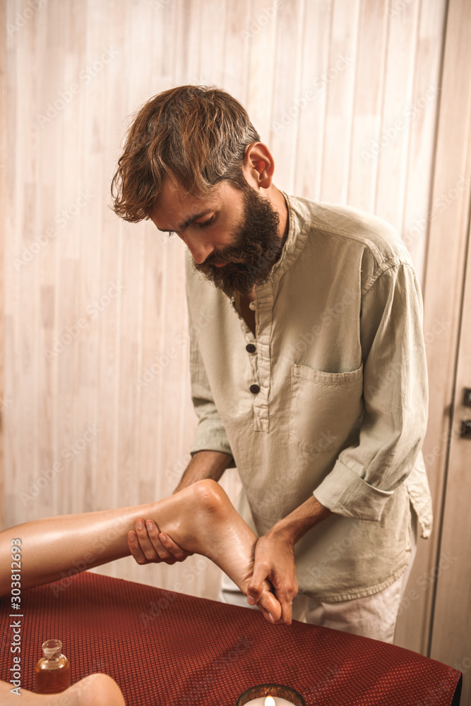 Alternative Medicine. Therapist healing woman doing abhyanga massage with herb infused oils rubbing foot concentrated Alternative Medicine. Therapist healing woman doing abhyanga massage with herb infused oils rubbing foot concentrated