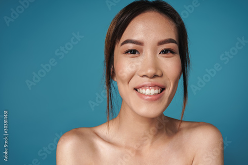Positive smiling asian woman posing naked isolated
