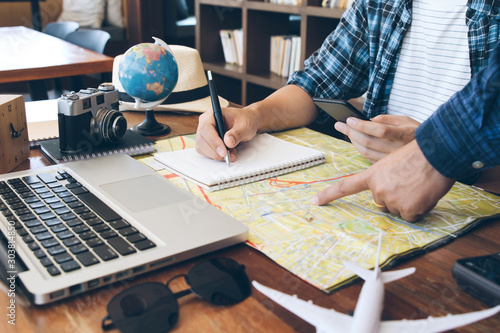 Travelling concept.Two men choosing place of vacation, exploring compromise on map, taking notes in notebook photo