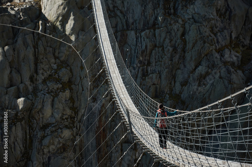 Fototapeta Naklejka Na Ścianę i Meble -  Mountaineers crossing the suspension bridge of Trift (Triftbrücke). Switzerland