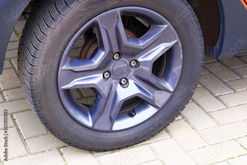 Car wheel, close up. Auto is parked in its parking spot in city.