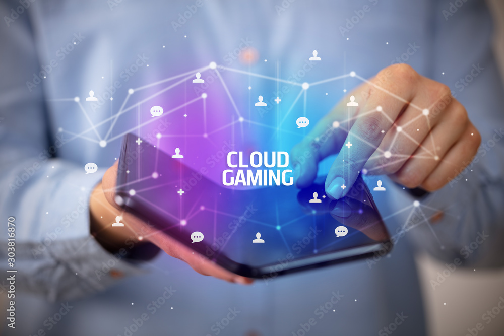 Businessman holding a foldable smartphone with CLOUD GAMING inscription, new technology concept Businessman holding a foldable smartphone with CLOUD GAMING inscription, new technology concept