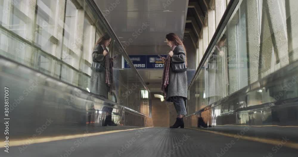 custom made wallpaper toronto digitalFemale traveler moving on travellator to departure indoors natural light. Fashionable woman standing on moving sidewalk holding smartphone indoors airport building. Travelling business trips transport