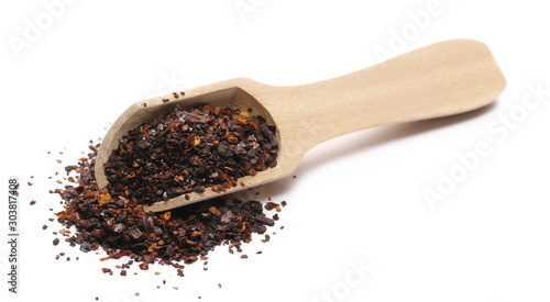 Roasted ground dry chili pepper pile, spicy chopped paprika with wooden spoon isolated on white background