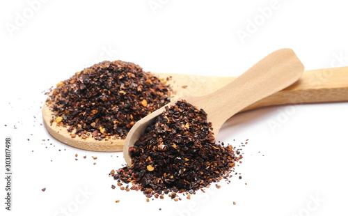 Roasted ground dry chili pepper pile, spicy chopped paprika with wooden spoon isolated on white background