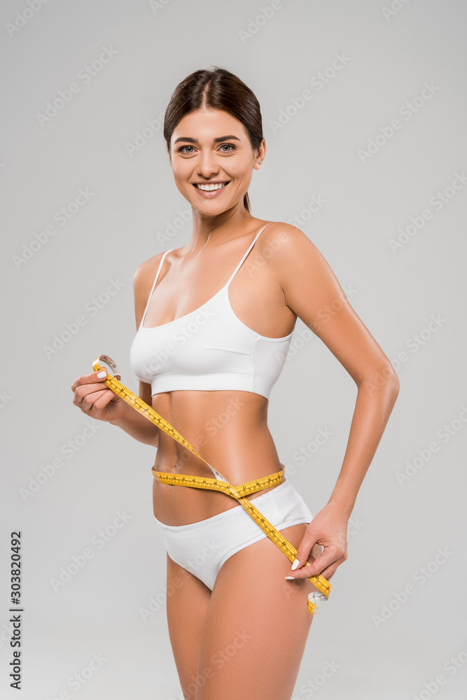 Φωτογραφία happy beautiful slim woman in underwear holding measuring tape on waist isolated
