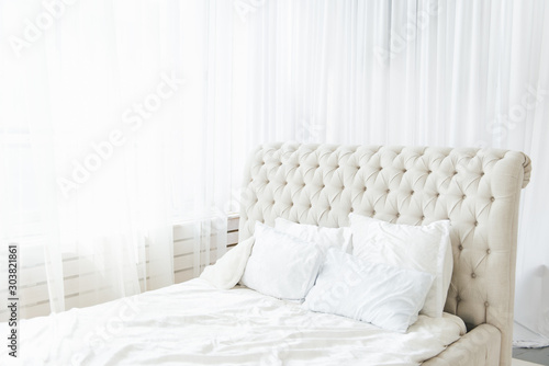 White bedroom with light bed and high headboard  light from the window