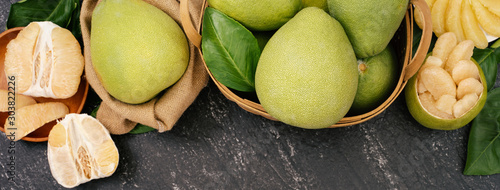 Fresh peeled pomelo, pummelo, grapefruit, shaddock on dark background in bamboo basket. Autumn seasonal fruit, top view, flat lay, tabletop shot.