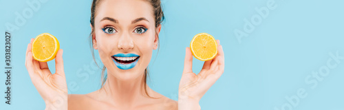 excited naked beautiful woman with blue lips holding orange halves isolated o...