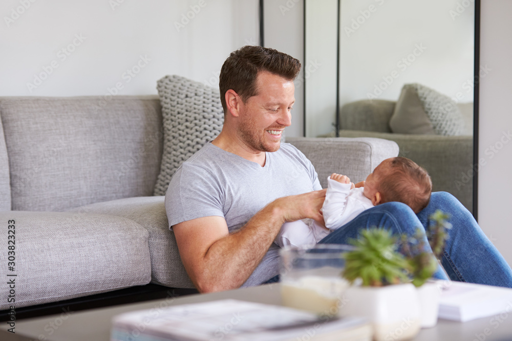 Baby Daughter Lying On Fathers Lap As He Plays Game With Her At Home Baby Daughter Lying On Fathers Lap As He Plays Game With Her At Home