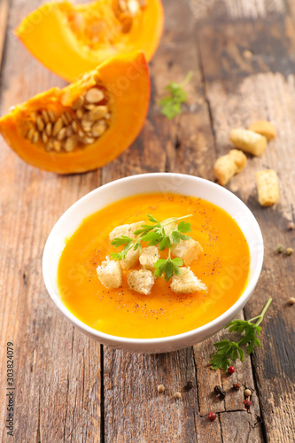 pumpkin soup in bowl with crouton on wood background