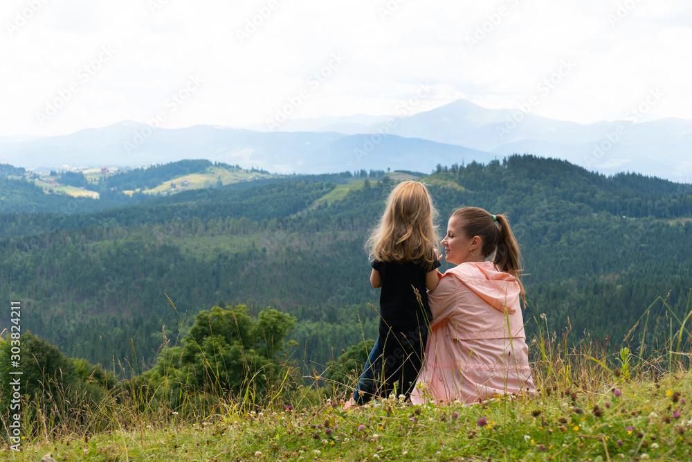 Woman and child girl having fun with mountain view behind
