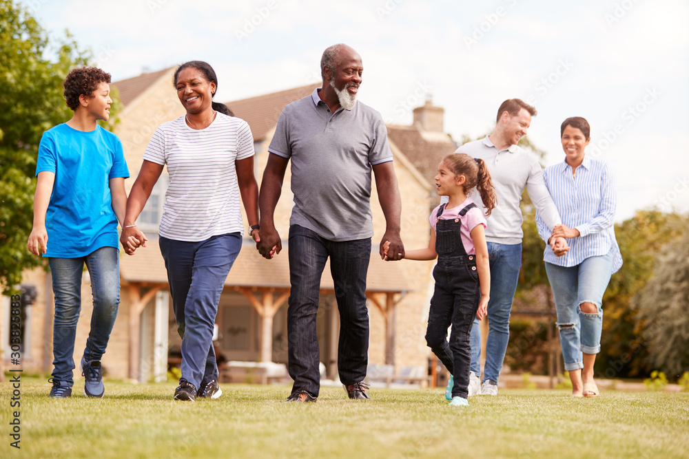 Smiling Multi-Generation Mixed Race Family Walking In Garden At Home Smiling Multi-Generation Mixed Race Family Walking In Garden At Home