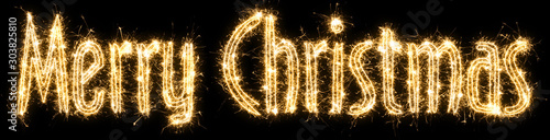 English text Merry Christmas written sparkling sparklers . Hand lettering isolated on black background. Beautiful glowing overlay template for holiday greeting card , banner , decoration site .