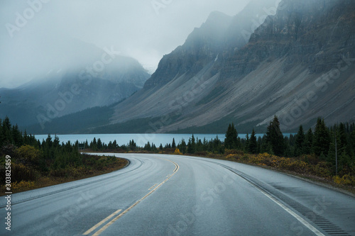 Scenic road trip with rocky mountain and lake in gloomy day photo