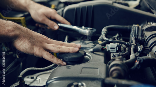 Hand von Mechatroniker am Auto bei Inspektion