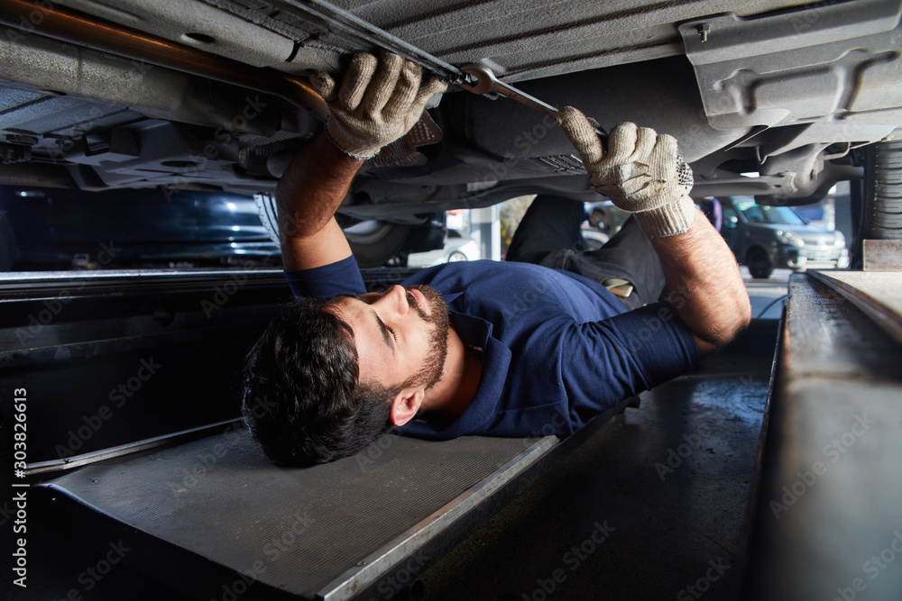 KFZ Mechaniker kontrolliert Auto Unterbodenschutz Stock Photo