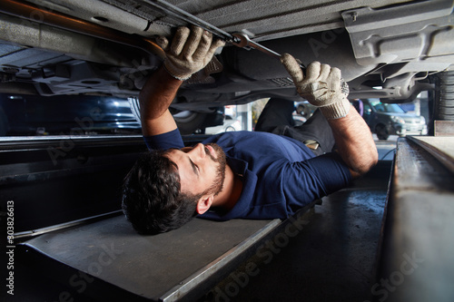 KFZ Mechaniker kontrolliert Auto Unterbodenschutz photo