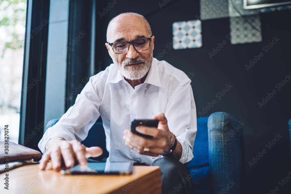 Bald senior man with eyeglasses using smartphone Bald senior man with eyeglasses using smartphone