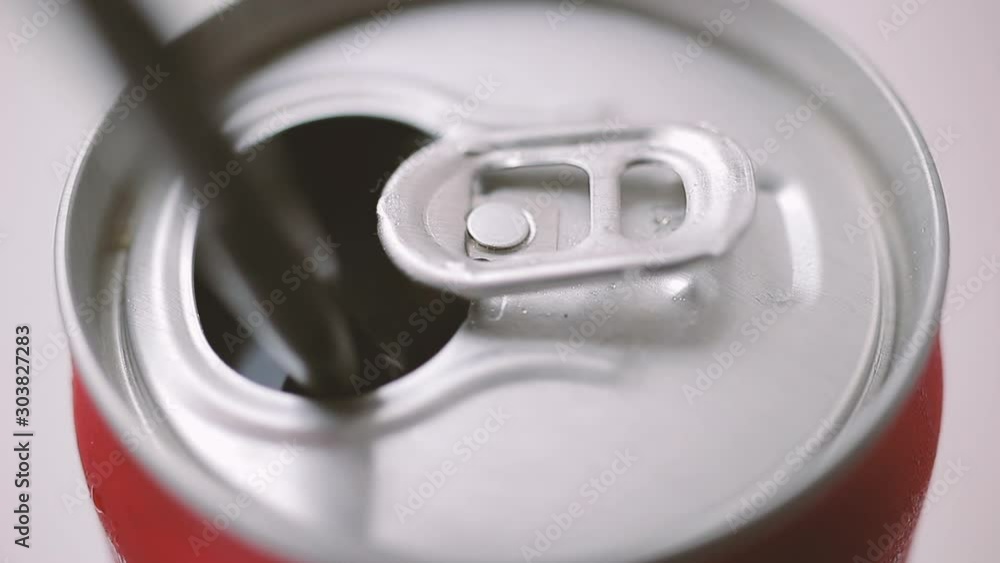 Putting straw into can with soda drink, close-up Putting straw into can with soda drink, close-up