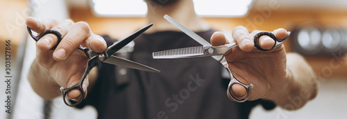 Professional hairdresser prepares for a haircut, checks his tool, examines scissors holding them in his hands, focus on scissors. concept for barbershops, beauty salons and hairdressers photo