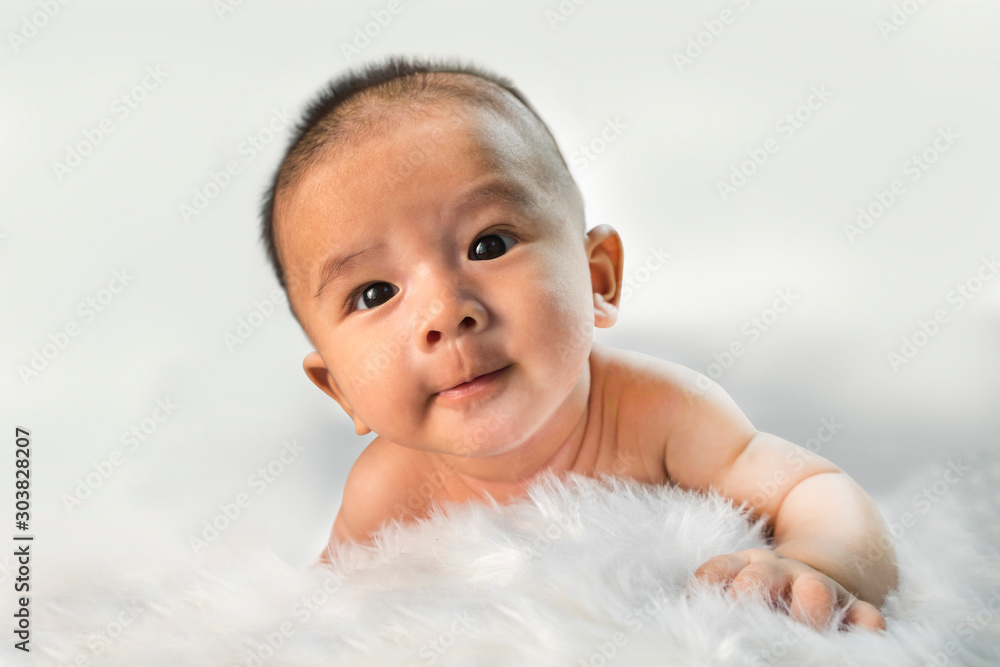Peaceful newborn baby lying on a bed smiling on white sheets Peaceful newborn baby lying on a bed smiling on white sheets