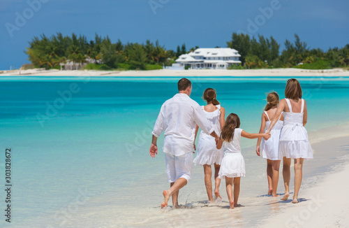 Happy Caucasian family in white walking on beach