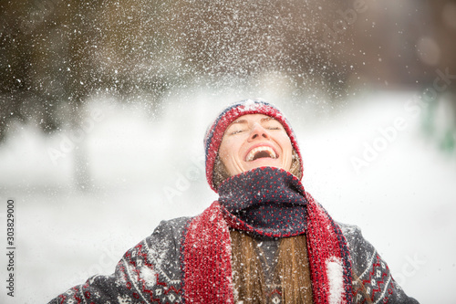 Happy beautiful woman having fun with snow outdoors in winter scenery