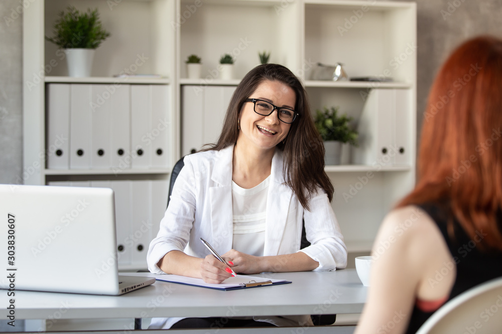 Smilng manager talks with her new employee and making notes. Selective focus Smilng manager talks with her new employee and making notes. Selective focus