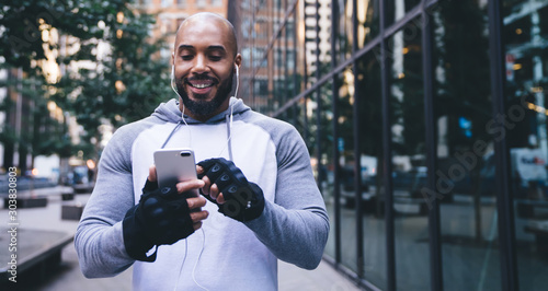 Joyful African American sportsman texting in social network