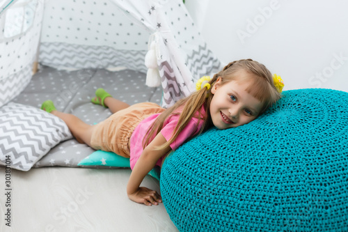 little girl on a children's ottoman near a wigwam photo