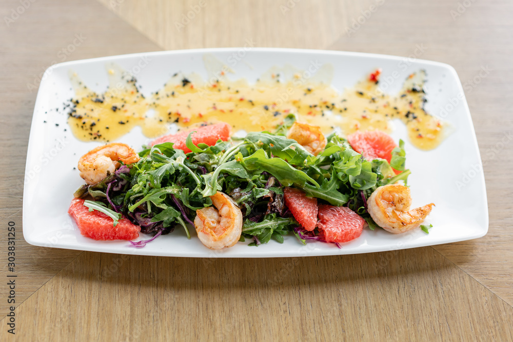 Delicious dish with grilled shrimps, slice grapefruit and arugula salad and spicy fried prawns. Restaurant menu, natural and organic food concept. Delicious dish with grilled shrimps, slice grapefruit and arugula salad and spicy fried prawns. Restaurant menu, natural and organic food concept.