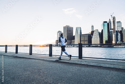 Strong male jogging on track in megapolis