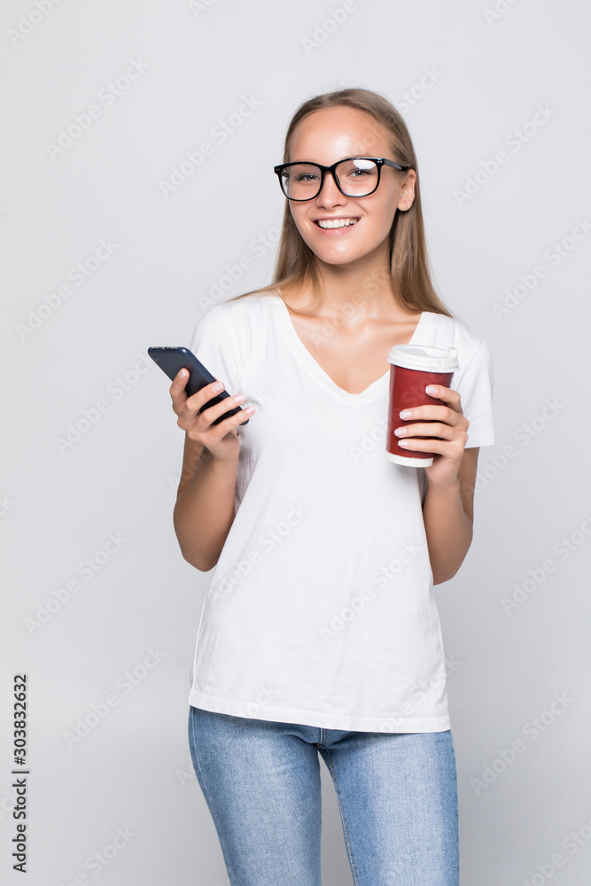 Close up portrait of a smiling pretty woman in hat holding mobile phone isolated over gray background Close up portrait of a smiling pretty woman in hat holding mobile phone isolated over gray background