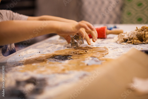 a child cuts a gingerbread cookie with a cookie cutter on New Year's Eve © Виктория Попова