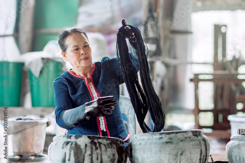 Asian woman In traditional dress Indigo dyeing Before being woven into fabric which is a product Which has built a reputation for Sakon Nakhon Province, Thailand. photo